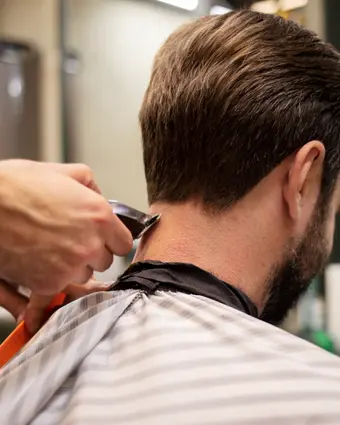 Bearded client mid-haircut, sides blended into a skin fade