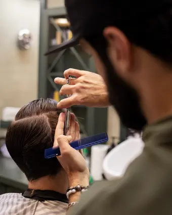Barber shaping the top with scissors and comb