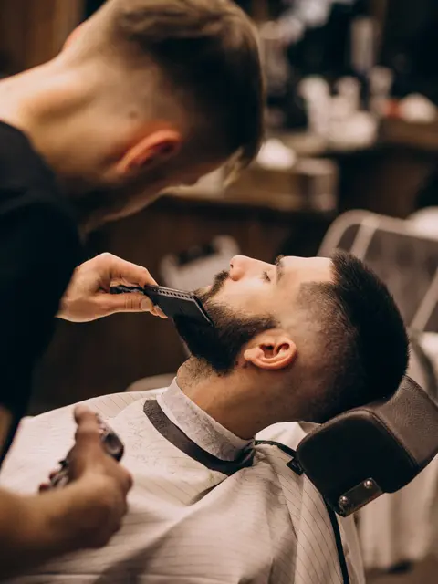 Barber trimming a client's beard at Razor & Oak
